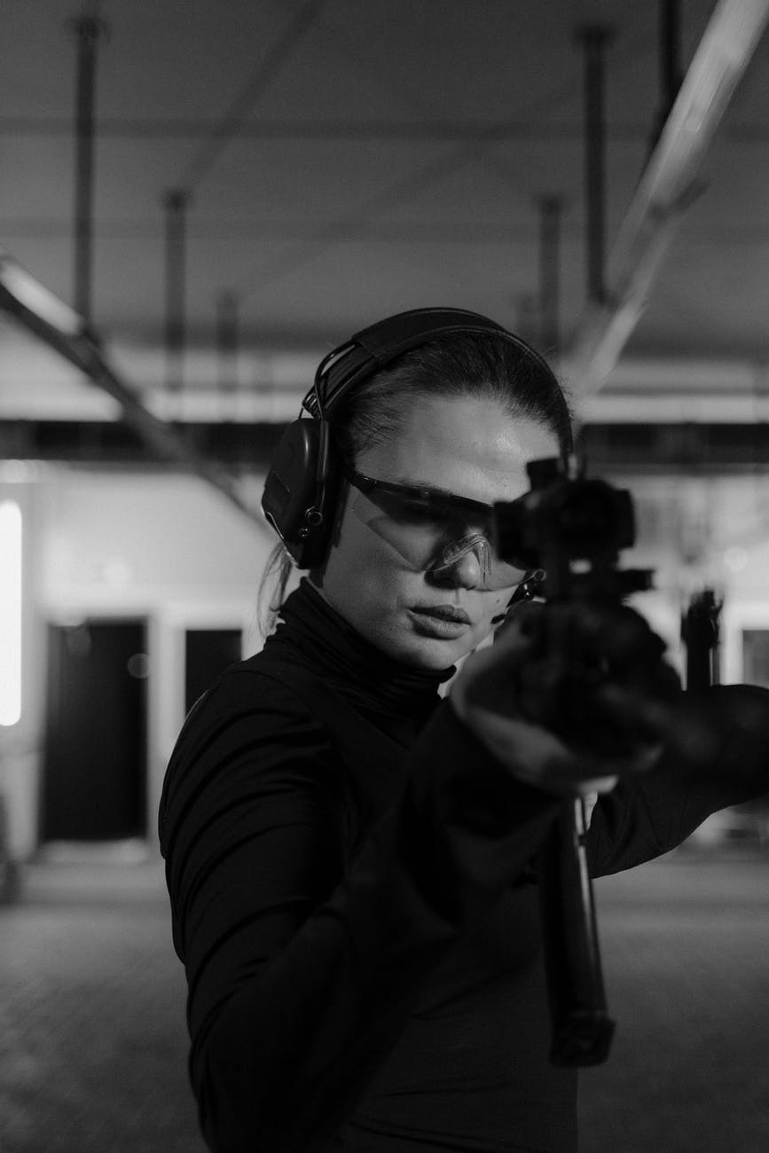 woman holding a black rifle in grayscale photography