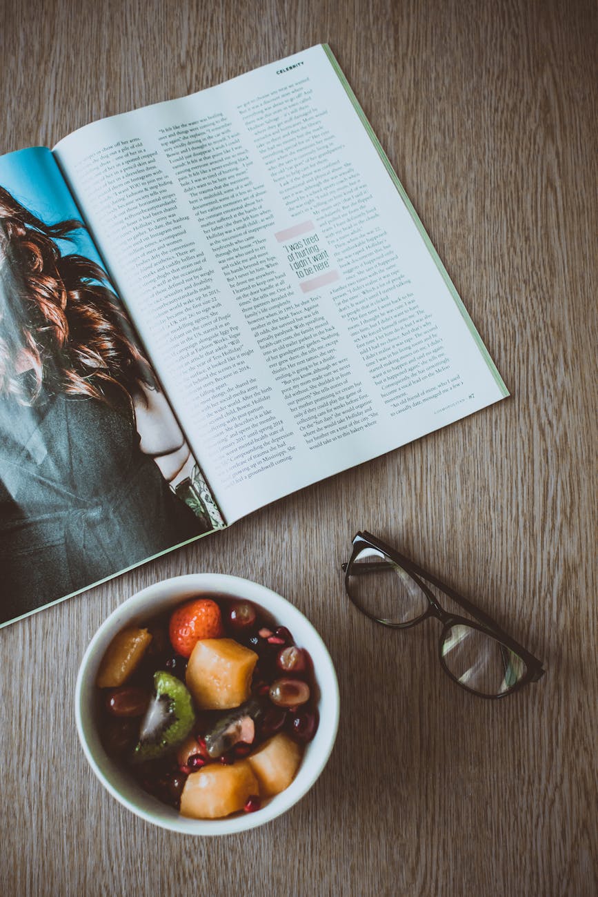 eyeglasses beside bowl of food and magazine on table